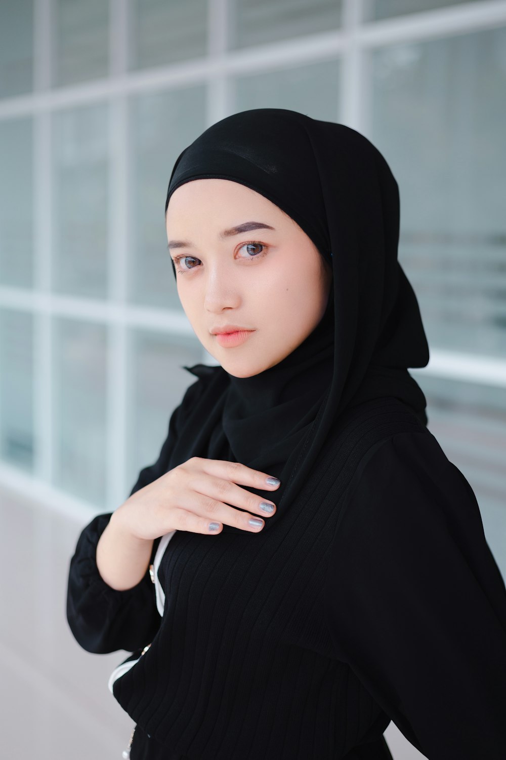 a woman wearing a black hijab standing in front of a building