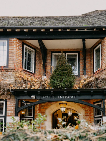 A warm, welcoming concierge greeting guests at a charming half-timbered house in Troyes.
