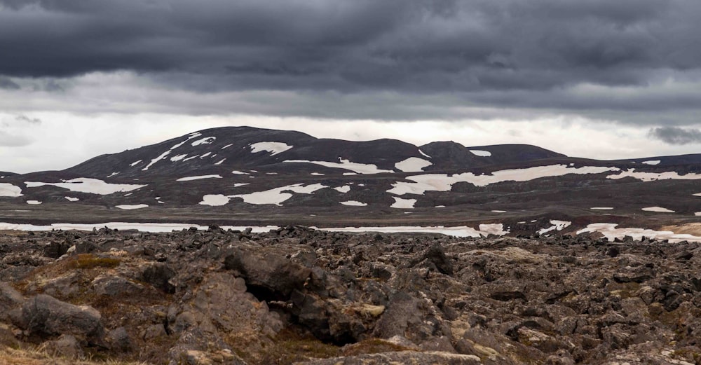 a mountain range covered in snow under a cloudy sky