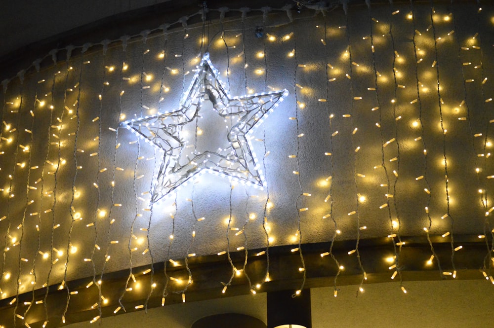 a lighted star hanging from the side of a building