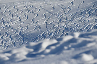 Close-up of fresh snow on ski tracks with ski equipment nearby