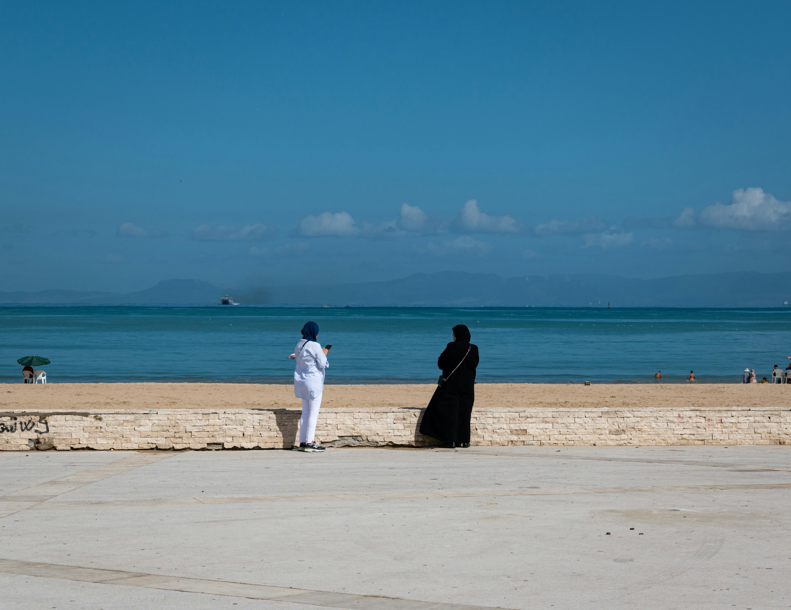 a couple of people standing on a beach next to the ocean