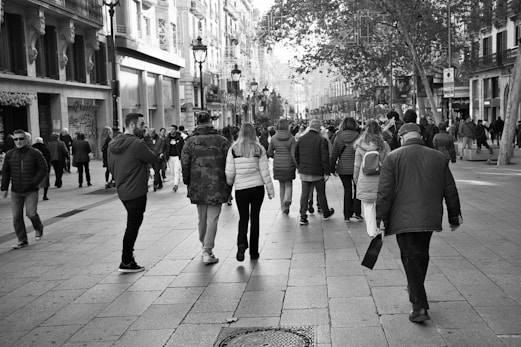 a group of people walking down a street next to tall buildings