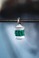 A silver padlock with green mechanical dials is hanging from a metal rod. The dials have white letters on them and appear worn over time. The background is blurred with a gradient of blue and dark shades.