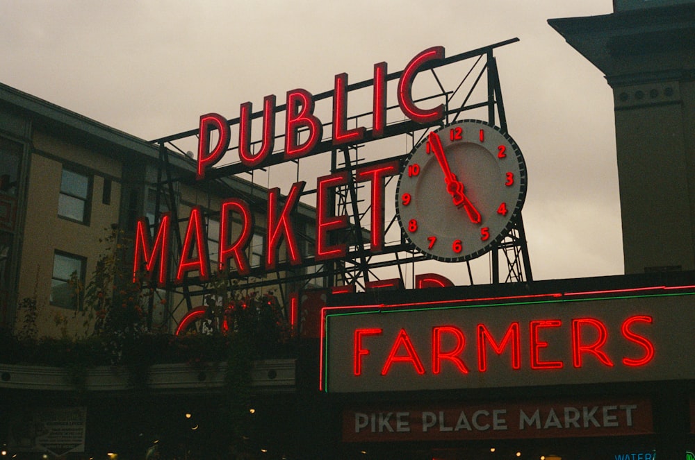 a large neon sign with a clock on top of it