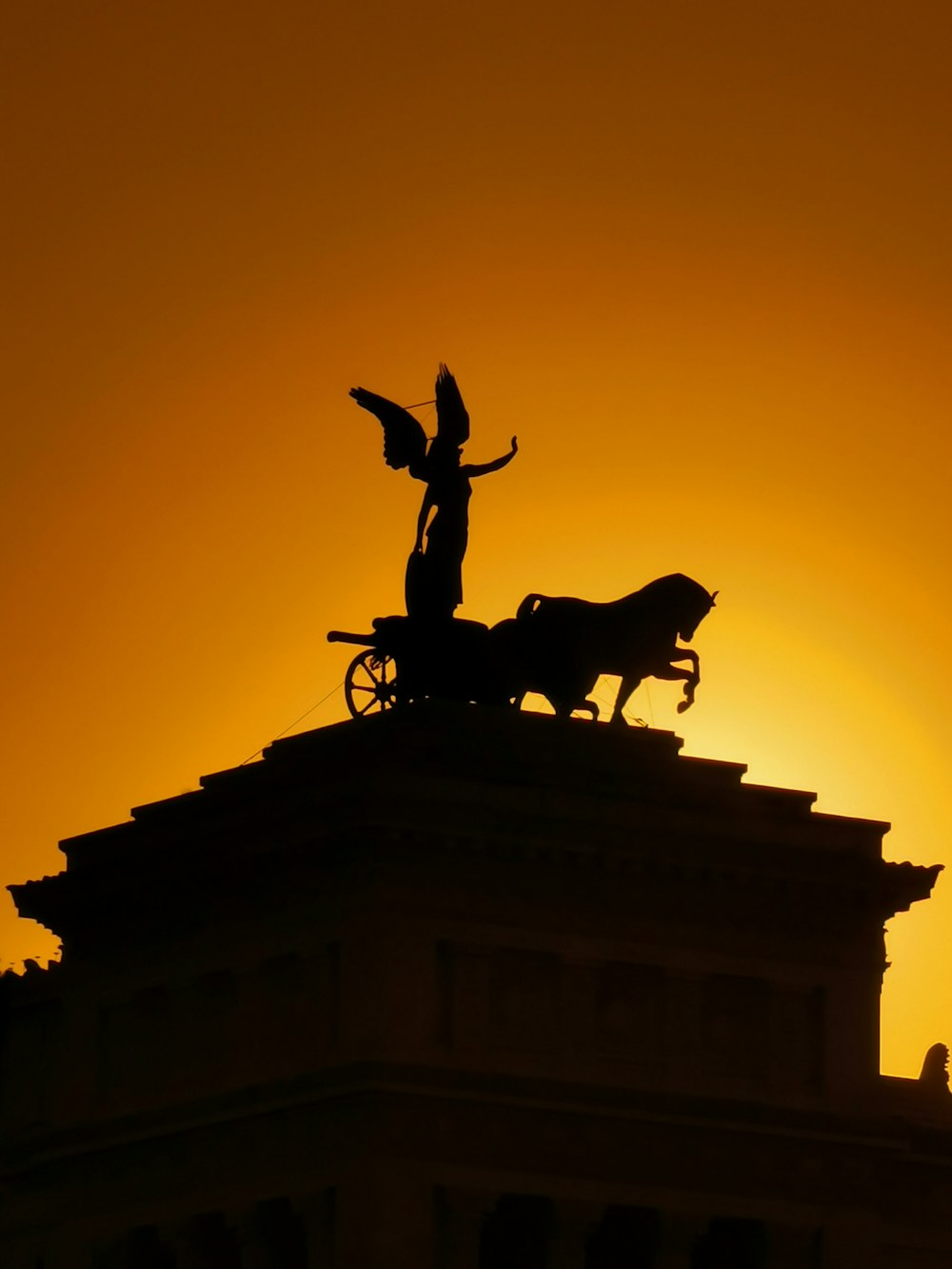 a statue on top of a building with the sun in the background