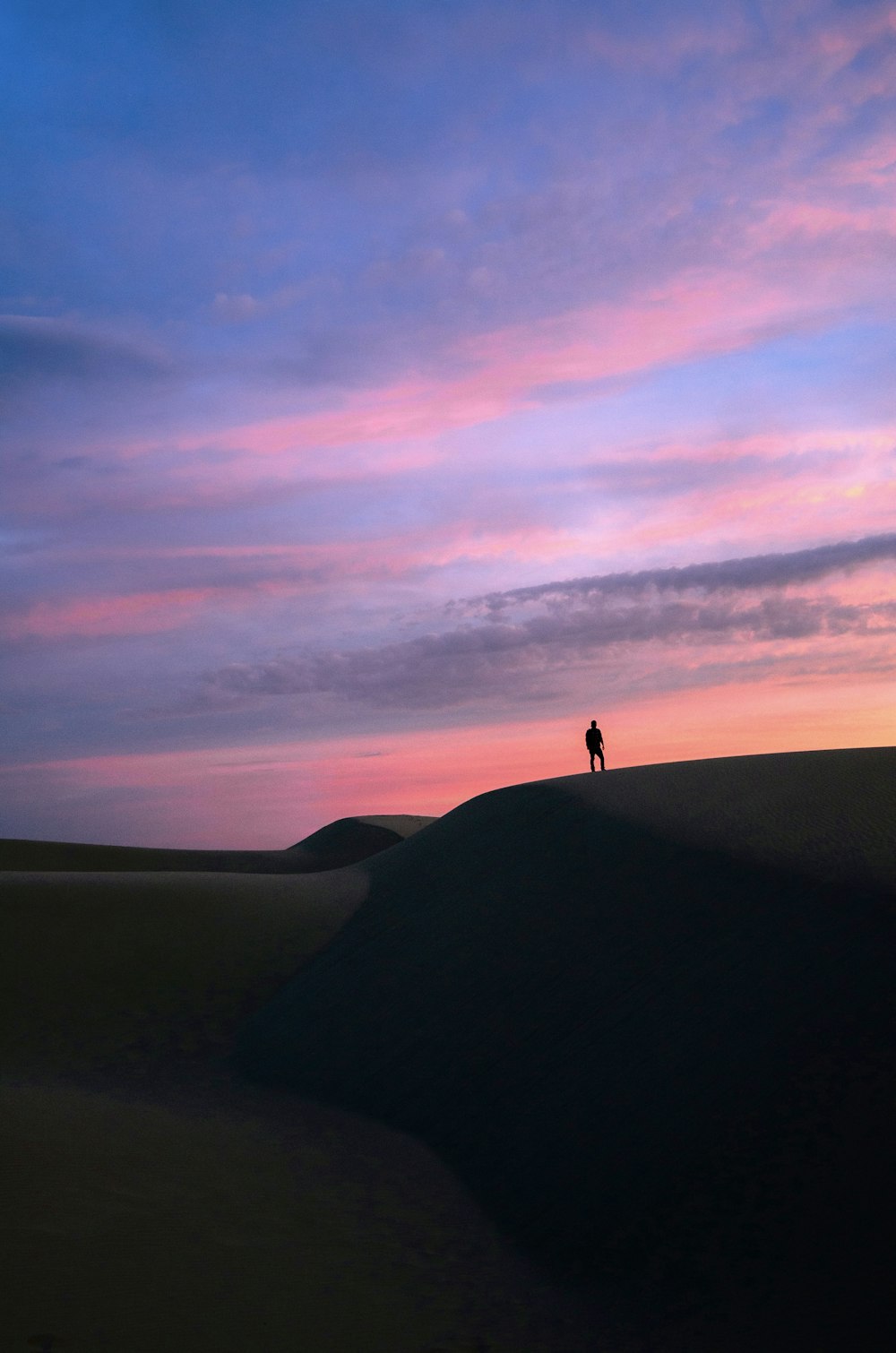 una persona de pie en la cima de una duna de arena