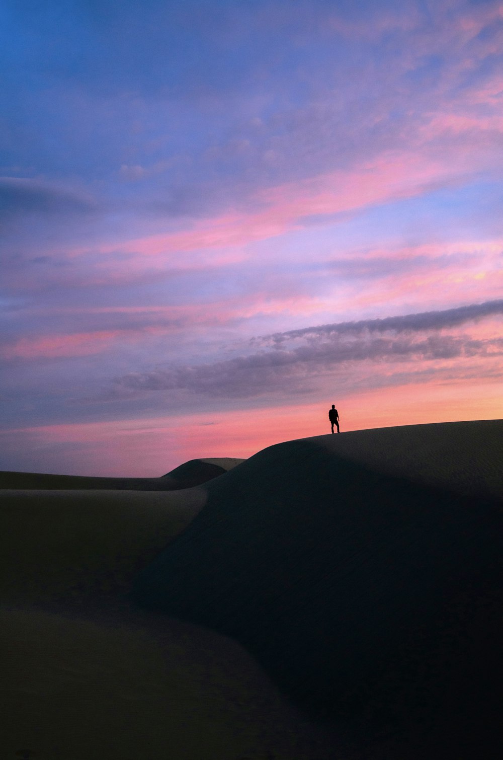 a person standing on top of a sand dune