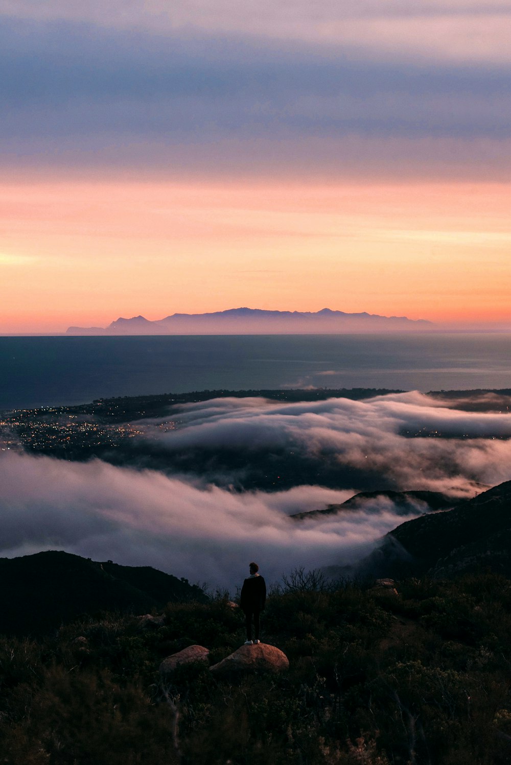 a person standing on top of a hill with a view of a city below