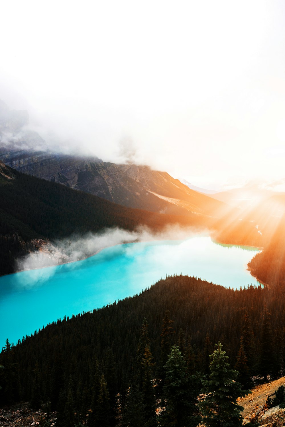 the sun is shining over a mountain lake