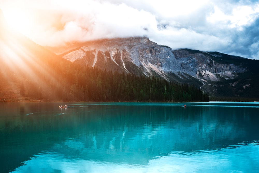 a lake surrounded by mountains under a cloudy sky