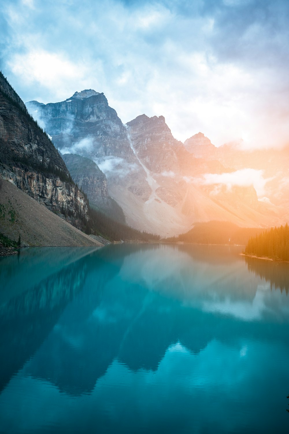 a lake surrounded by mountains under a cloudy sky