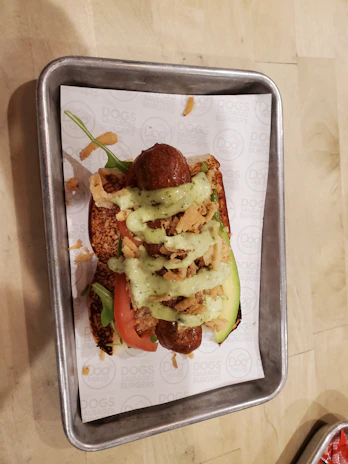 A vibrant plate of loaded hot dogs topped with crispy onions, cheese, and smoky sauce.