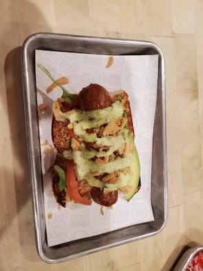 A loaded hot dog topped with crispy bacon, cheese, and smoky sauce on a warm bun.