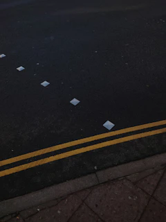 Workers installing reflective road studs along a curved highway at dusk with safety gear and machinery.