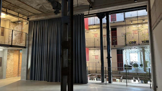 Industrial style curtains hanging in a sunlit loft with exposed brick walls.