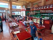 The lively interior of the restaurant with green-themed decor and customers enjoying their meals.