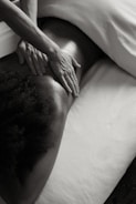a person laying on a bed with their hands on their back
