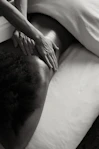 a person laying on a bed with their hands on their back