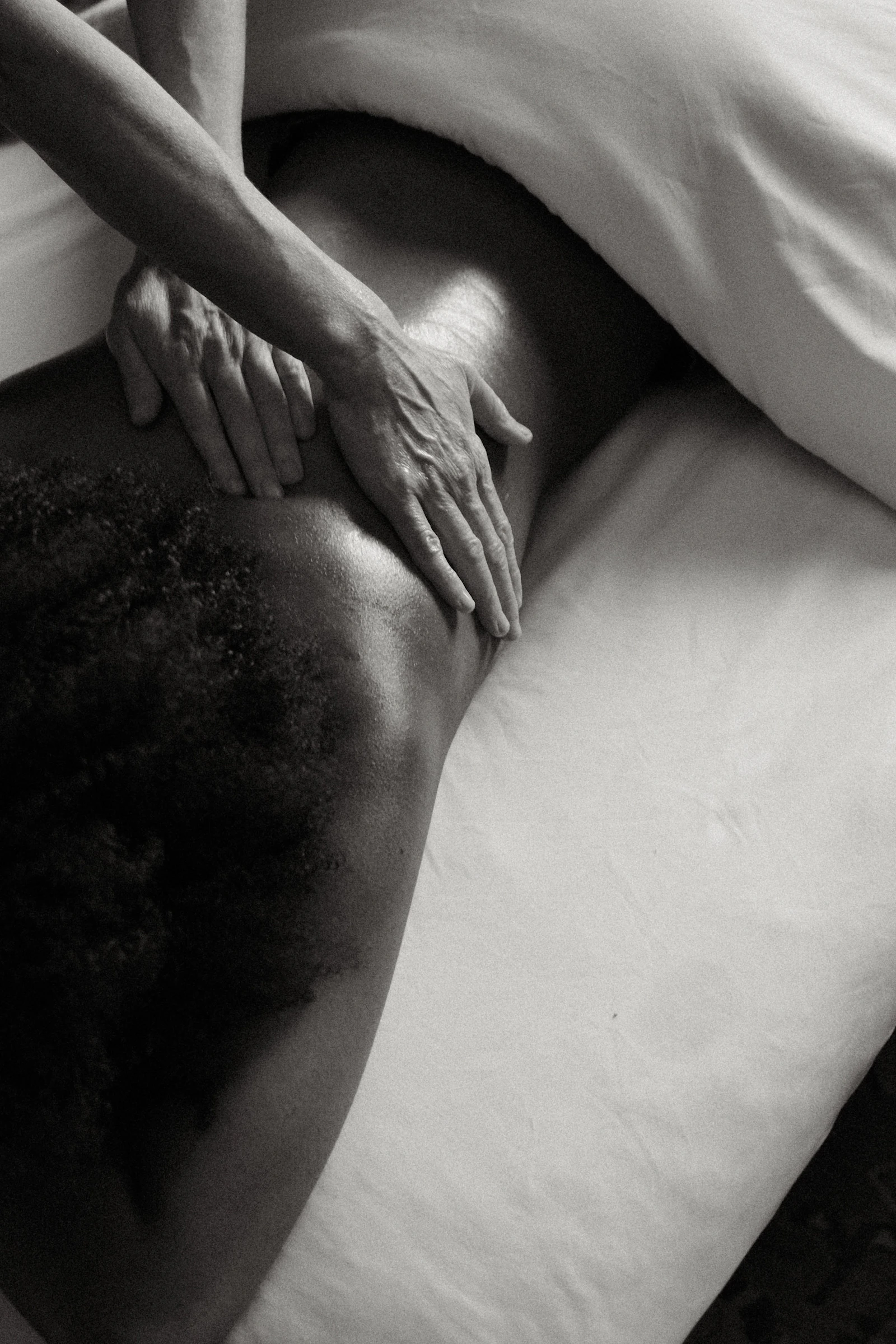 Person lying on a bed receiving gentle touch, representing physical intimacy, comfort and body memory
