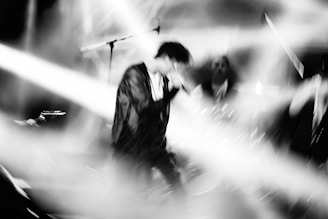 Black and white image of a live performance with dynamic lighting.