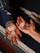 Two hands are holding a collection of crystals of various shapes and colors, positioned above a textured, multicolored fabric. The left hand, adorned with a beaded bracelet and rings, holds larger, white crystals, while the right hand holds smaller, varied stones.