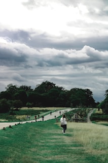a group of people walking down a grass covered road
