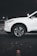A white SUV is parked in a dimly lit underground parking garage. The focus is on the front wheel and the side of the vehicle, highlighting its sleek design and modern alloy wheels. The setting has an industrial feel with concrete flooring and muted lighting.