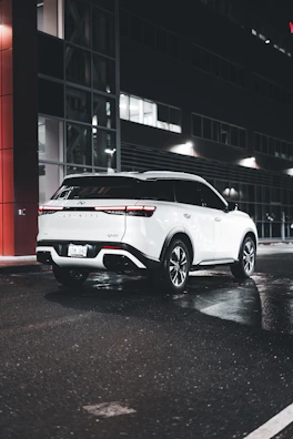 A spotless white SUV with gleaming paint protection finish parked on a city street.