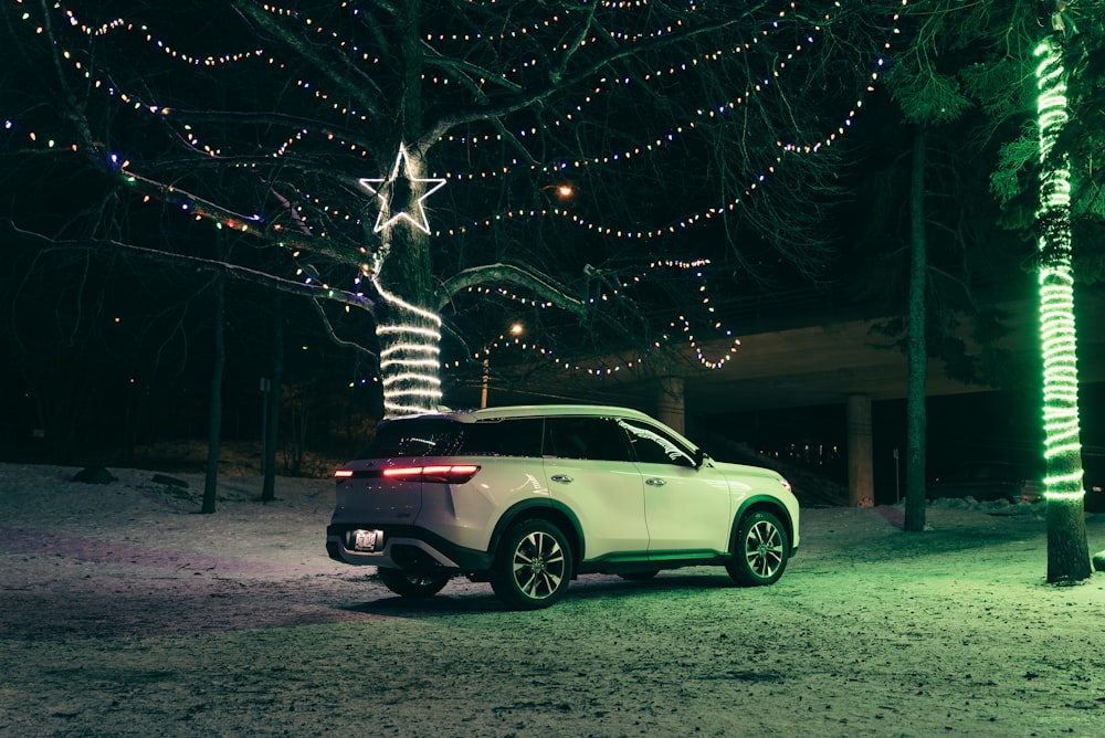 a white car parked in front of a christmas tree