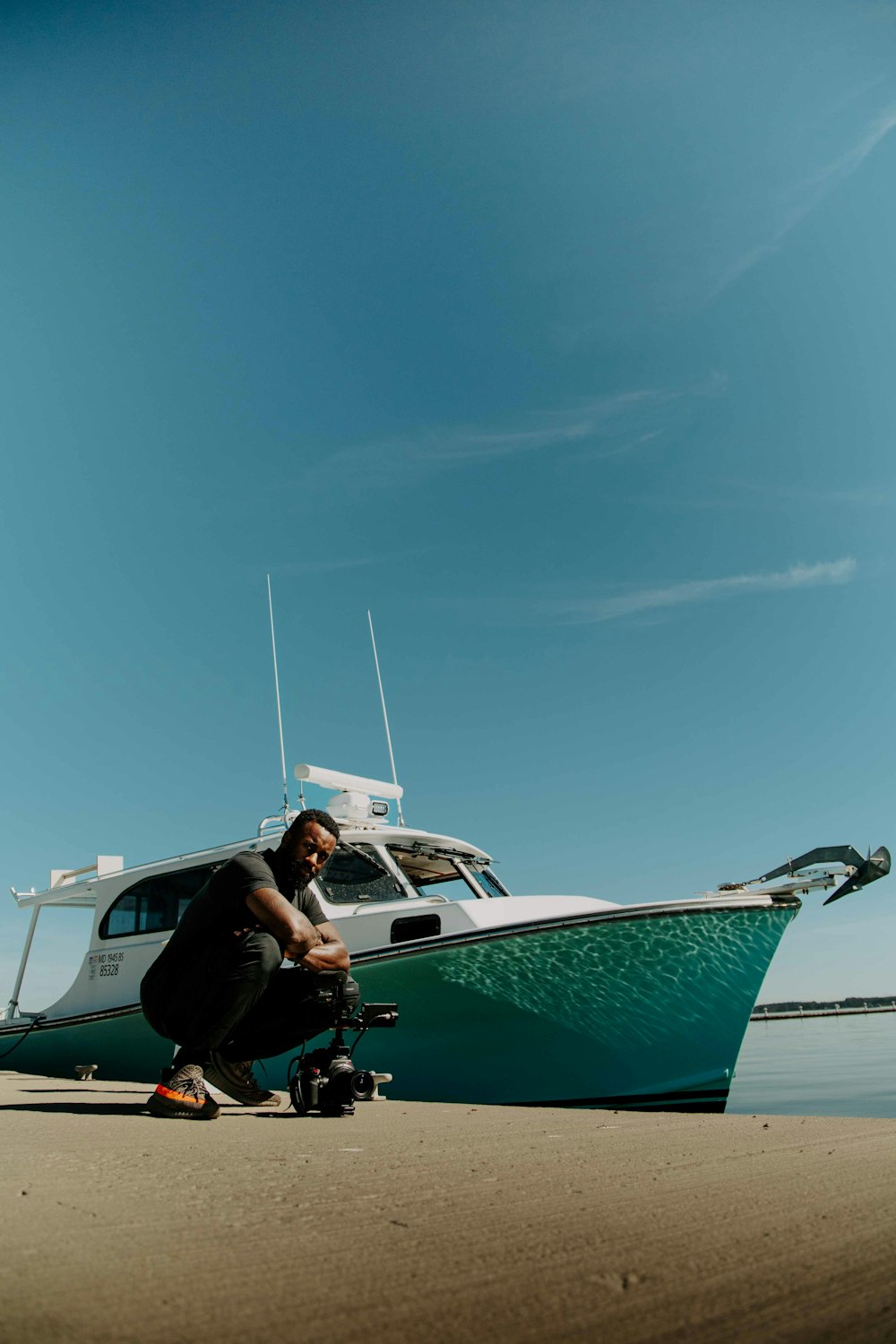 a man kneeling down next to a boat on the beach