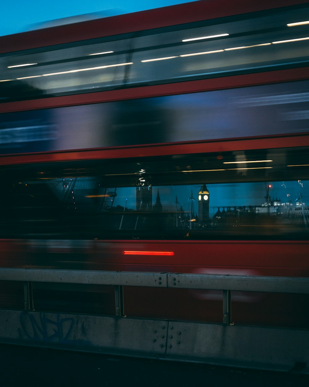 a red double decker bus traveling past a clock tower