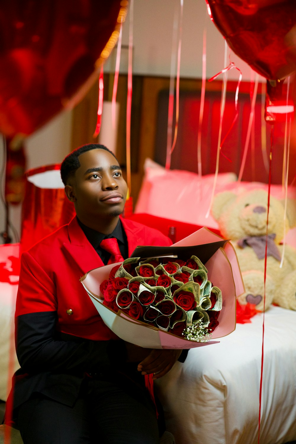 a man sitting on a bed holding a bouquet of roses