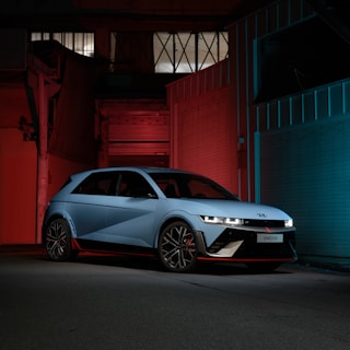 A sleek car freshly painted in navy blue with electric blue accents at Automotoria garage.
