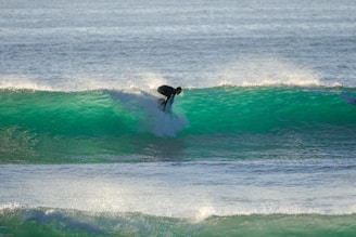 A surfer riding a vibrant evergrom surfboard on a sunny ocean wave, radiating energy and freedom.