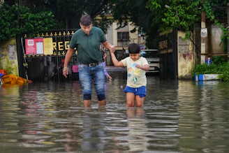 Rescue workers helping a homeless family cross through floodwaters with their meager belongings.