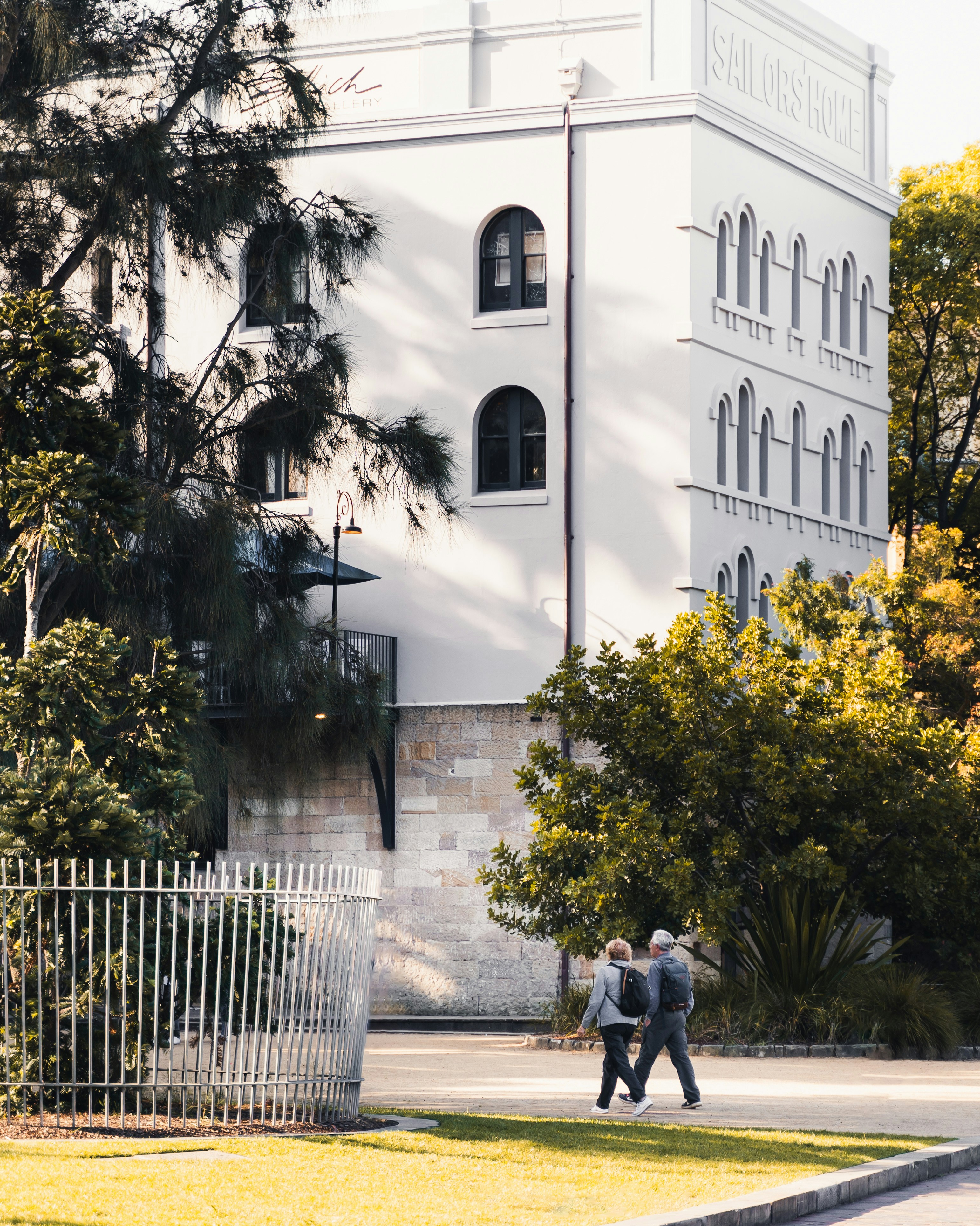 大きな白い建物の前を歩く2人