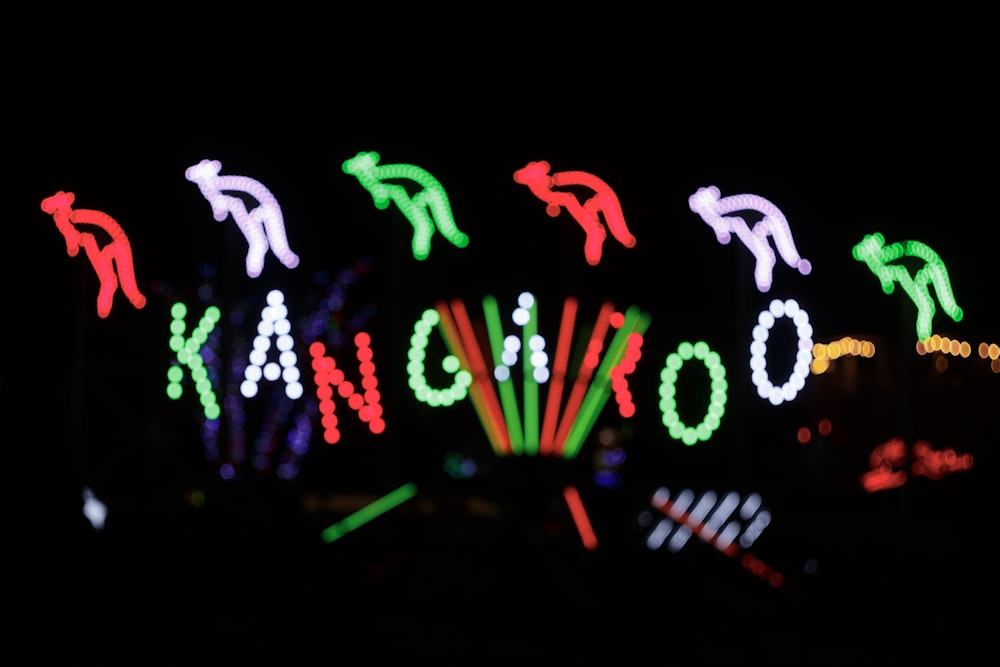 a carnival sign lit up at night with lights