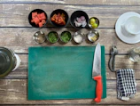 A sleek navy kitchen gadget set lined up beside a cutting board with chopped vegetables.