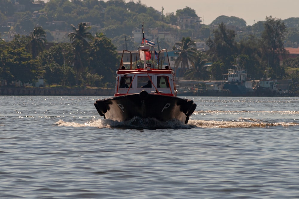 a red and white boat traveling across a body of water