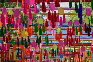 Colorful tassel garlands hanging above a bedside shelf, adding playfulness to the room