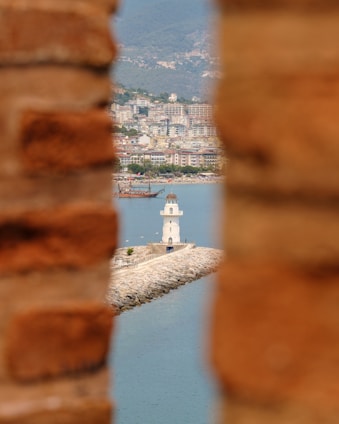 a view of a body of water through a hole in a brick wall