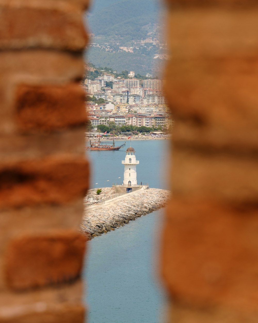 a view of a body of water through a hole in a brick wall