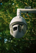 A sleek security camera mounted on a home exterior wall overlooking the yard