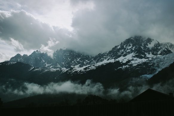 a mountain range covered in clouds and snow