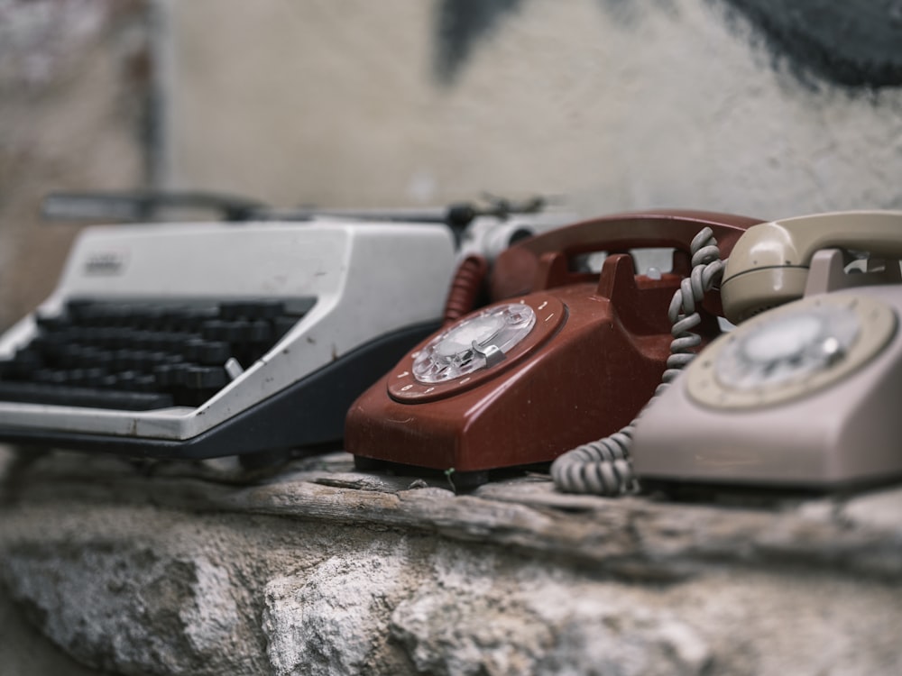 a couple of old fashioned telephones sitting on top of a rock