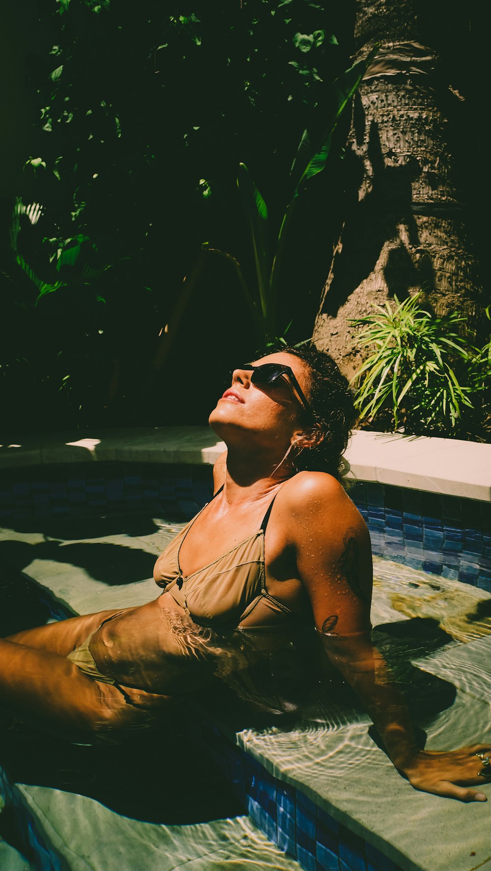 a woman sitting in a swimming pool with her eyes closed