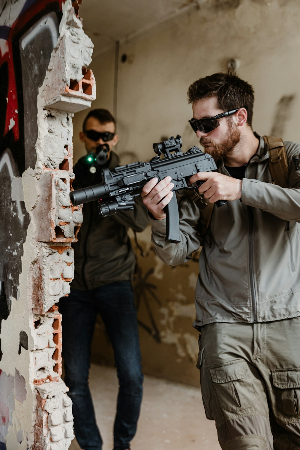 a man holding a gun in front of a brick wall