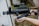 A person holding a tactical weapon with a cylindrical barrel and attached scope, standing outdoors. The weapon is predominantly black with a textured surface and appears to be designed for military or law enforcement use.