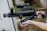 A person holding a tactical weapon with a cylindrical barrel and attached scope, standing outdoors. The weapon is predominantly black with a textured surface and appears to be designed for military or law enforcement use.
